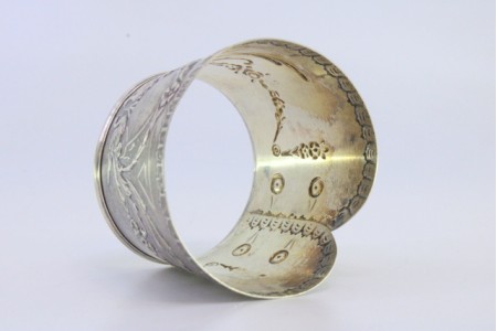 Argola de guardanapo em prata em forma de punho e relevada com motivos florais.